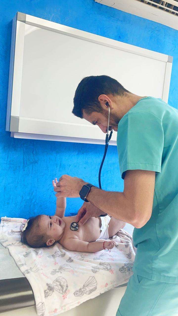 Dr. Marlon Cerna auscultando con estetoscopio a un bebé durante la consulta